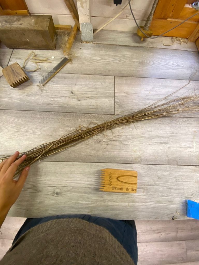 Flax fibre and combing tools laid out on a wooden floor