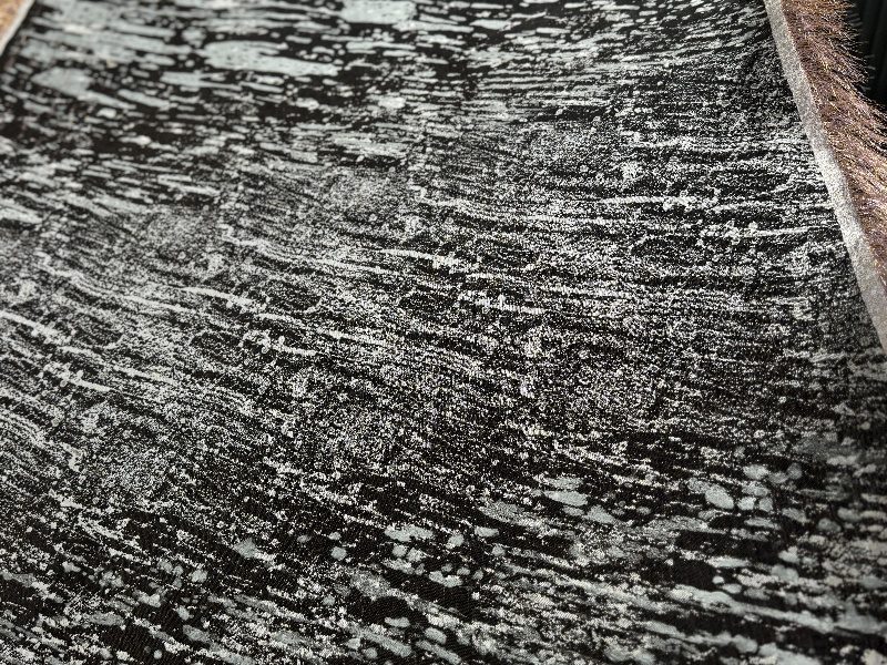 Close-up of a black and white Jacquard woven textile with metallic fringe