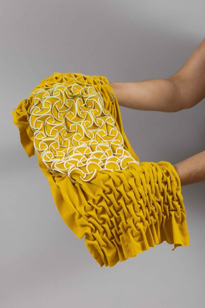 Yellow stretch fabric with 3D-printed smocking pattern forming raised texture